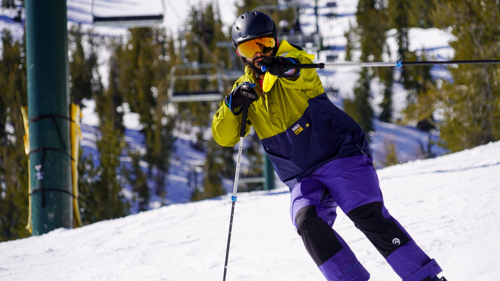 Skier in a yellow and purple jacket carving down a slope